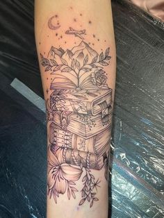 a tattoo on the leg of a woman with an open book and flowers around it