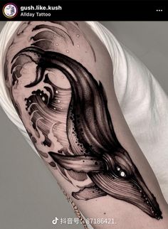 a black and white photo of a man's arm with a whale tattoo on it