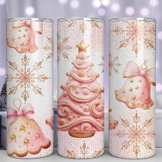 three christmas themed tumbles on a table with snowflakes and lights in the background