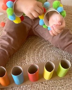 a child is sitting on the floor with four cups