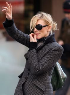 a woman in black and white jacket talking on cell phone while walking down the street