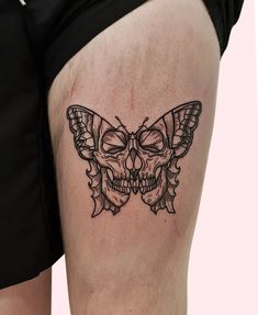 a woman's thigh with a skull and butterfly tattoo on it