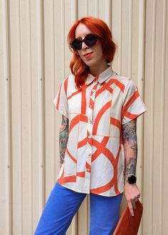 Slightly slouchy short sleeve collared shirt featuring a button down front and an abstract & grid print in bright orange, marigold, and beige. Beautifully soft linen-Tencel blend, so it's super soft and perfect for the warmer temps! Subtle hi-low hem (a bit shorter at front and longer at back) with side slits. Features: Collared short sleeve shirt Button up front Slightly slouchy fit Regular length Beige colorway orange abstract pattern Fabric covered buttons Linen-Tencel blend Unlined No stretc Stylish Button Up Shirts, Casual Summer Shirt With Geometric Pattern, Trendy Orange Cotton Blouse, Orange Collared Tops For Summer, Casual Orange Collared Blouse, Casual Collared Orange Blouse, Orange Collared Summer Blouse, Casual Orange Blouse With Graphic Print, Summer Orange Shirt With Relaxed Fit