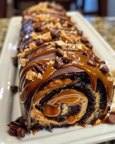 a chocolate roll covered in caramel and drizzled with icing on a white plate