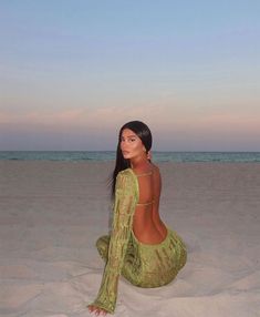 a woman is sitting on the sand at the beach