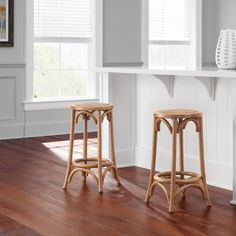 two wooden stools sitting on top of a hard wood floor next to a window