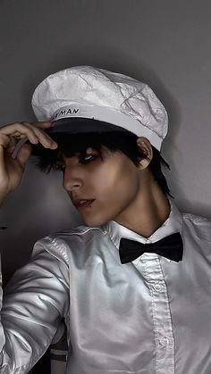 a woman wearing a silver shirt and bow tie with a white hat on her head