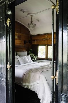 an open door leading to a bedroom with a bed and chandelier in it