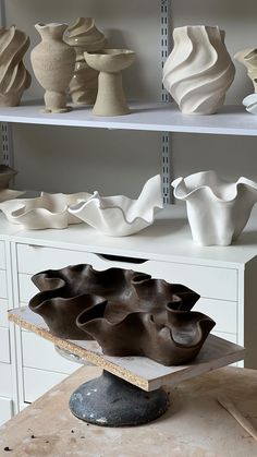 some white vases are sitting on shelves in a room that is being worked on