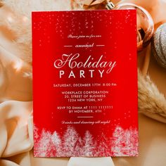 a red and white holiday party card on top of a table with ornaments around it