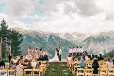 a group of people standing on top of a grass covered field next to wooden chairs