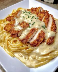 a white plate topped with pasta covered in sauce and chicken breast pieces on top of it