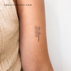 a woman's arm with a small flower tattoo on the left side of her arm