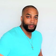 a man in a blue shirt with a cross on his chest is looking at the camera