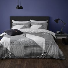 a bed with black and white comforter in a bedroom next to a blue wall