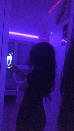 a woman standing in front of a purple light holding a cell phone to her ear