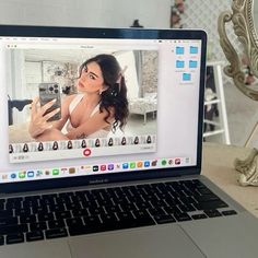 an open laptop computer sitting on top of a wooden table next to a white vase