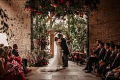 a bride and groom standing in front of an arch with flowers on it at their wedding ceremony