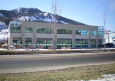 an office building on the side of a road with snow covered mountains in the background