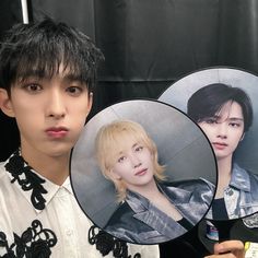 a young man holding up two pictures of him and the same person in front of them