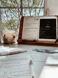 an open laptop computer sitting on top of a desk next to a notebook and pen