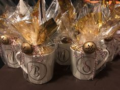 three coffee mugs decorated with gold and silver christmas balls, wrapped in cellophane