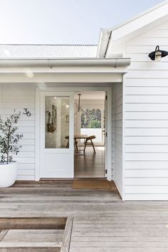 a white house with a wooden deck and potted plants on the front door area