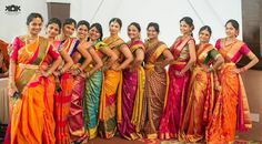 a group of women standing next to each other in colorful sari dresses and holding bouquets