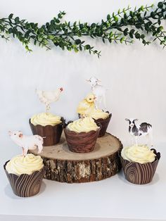 cupcakes with frosting and small figurines sitting on top of a tree stump