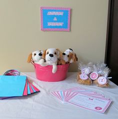 there are stuffed dogs in a pink bucket on the table with cards and envelopes