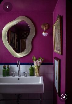 there is a sink and mirror in this bathroom with purple walls, white tile flooring and pink accents