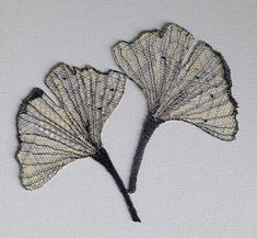 two leaf shaped brooches sitting on top of a white surface