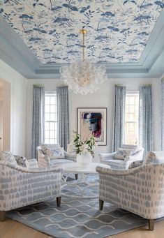 a living room filled with furniture and a chandelier hanging from the sky ceiling