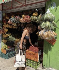 a woman standing in front of a fruit stand