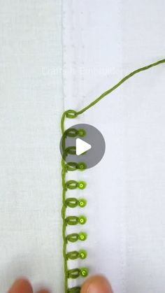 someone crocheting the end of a piece of fabric with green yarn on it