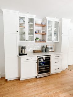 a kitchen with white cabinets and wood floors