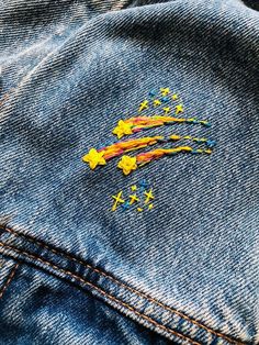 a pair of blue jeans with yellow stars painted on the back and bottom of them