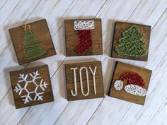 four wooden blocks decorated with christmas decorations and the words joy written in white yarn on them