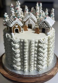 a white cake decorated with gingerbread houses and trees