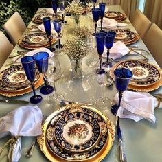 the table is set with blue and gold china plates, silverware, and napkins