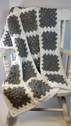 a crocheted blanket sitting on top of a wooden chair next to a white rocking chair