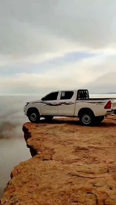 a white truck parked on top of a rocky cliff