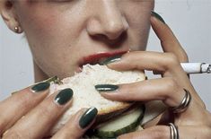 a woman with green nails eating a sandwich