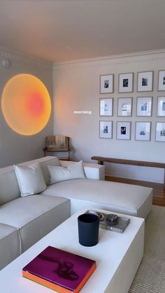 a living room with white couches and pictures on the wall above them, along with a coffee table