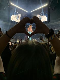 someone making a heart with their hands at a concert