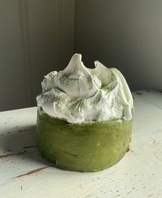 a green cake with whipped cream on top