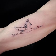 a small tattoo on the arm of a woman with a bird flying over her shoulder