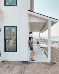 a woman standing on the side of a white building