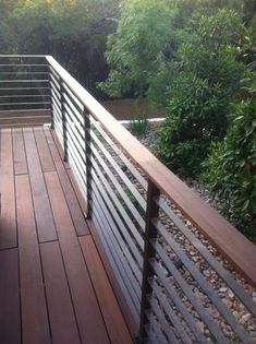 a wooden deck with metal railings and trees in the background