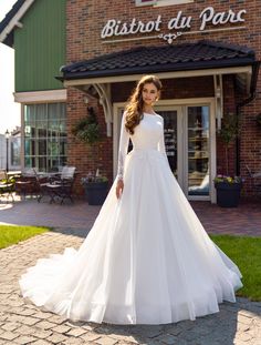 a woman in a white wedding dress standing on a brick walkway outside a store front